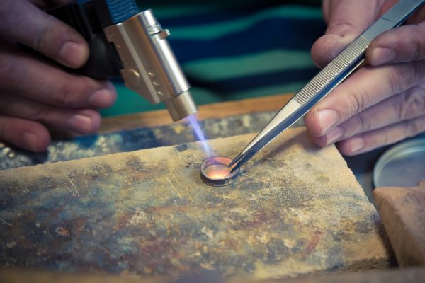 Goldsmith working with Bunsen burner and mould wedding ring shape